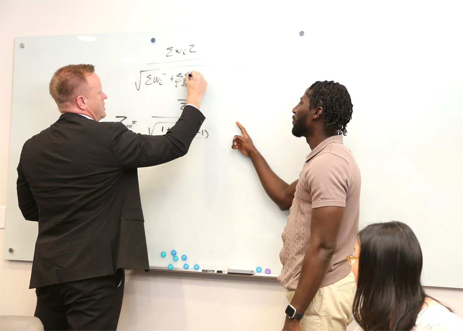 Two Pentara statisticians working through a derivation on the whiteboard in the Millcreek office